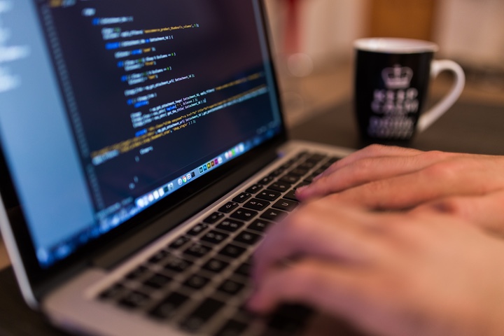 Hands typing on a laptop with code on the screen