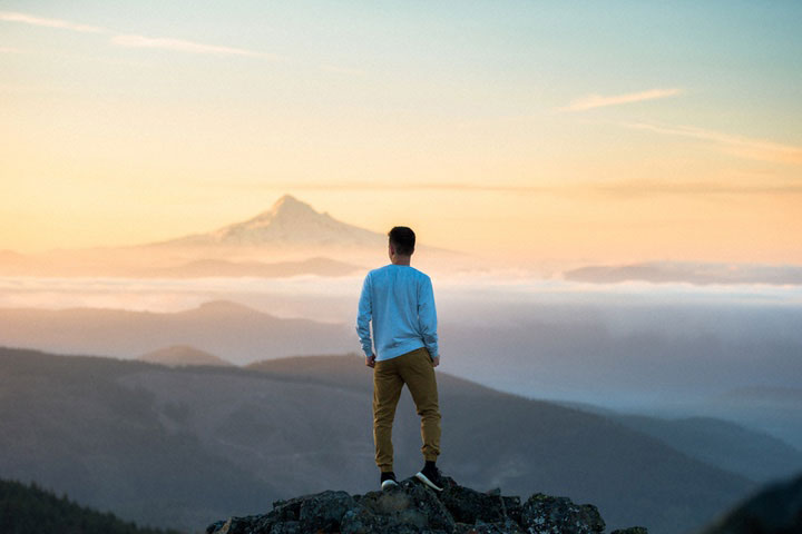 A man stood on a mountain top looking towards the horizon